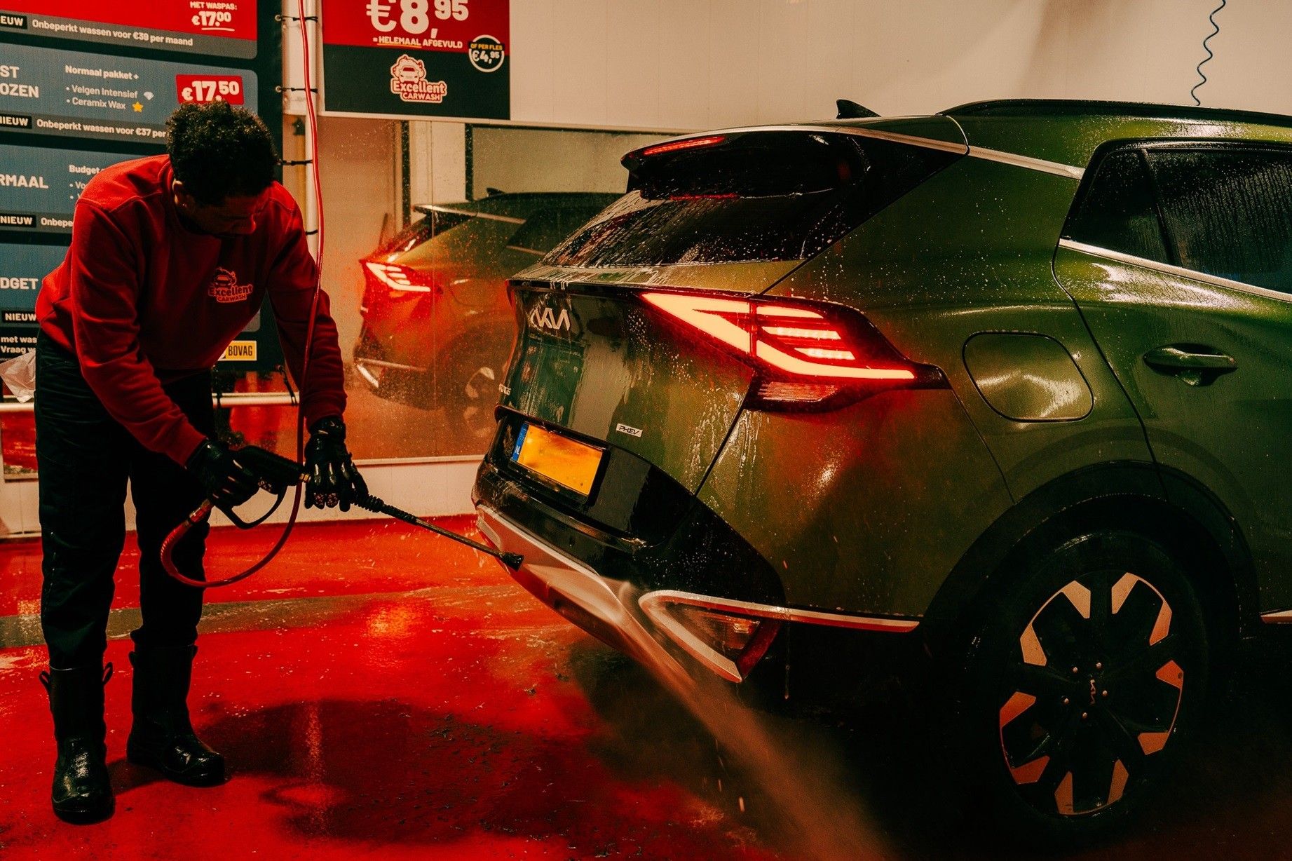 Medewerker reinigt met een hogedrukspuit de achterzijde van een auto bij Excellent Carwash Amsterdam.